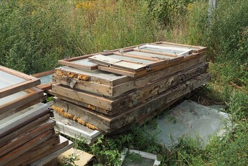 garbage from old wooden window frames with broken glass in a heap in green grass on the street