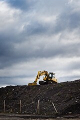 A yellow excavator on top of a gravel embankment - 459134525