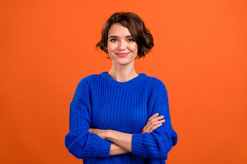 Photo of optimistic brunette hair young lady crossed arms wear blue sweater isolated on orange color background