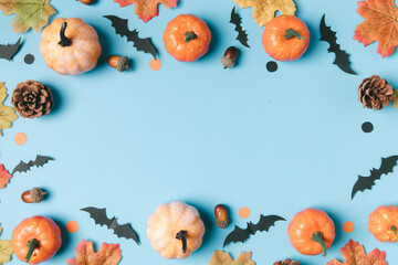 halloween and decoration concept  pumpkins and black paper bats flying over light blue background