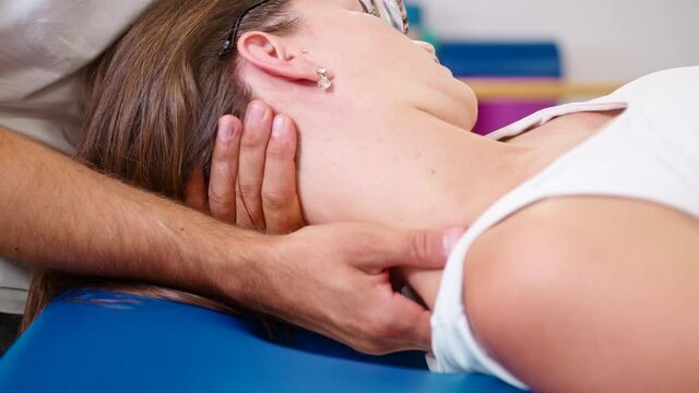 Close up shot of male Caucasian hands doing manual joint neck stretching and giving a neck massage to a young Caucasian woman