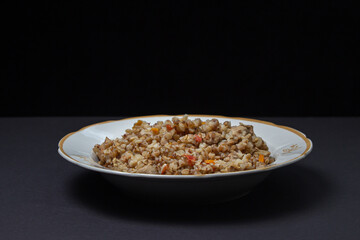 Buckwheat with meat on a black background. Delicious and healthy diet food