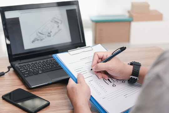 Car service staff use a pen check list in document with spare parts in stock on and check to assess the price of the insurance notification : Car insurance business concept