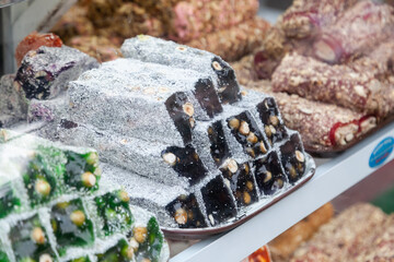 In front of store selling Turkish delight, various locum, arranged like pyramid, with knives, colorful sweets, ready to taste, in Spice bazaar Kemer.