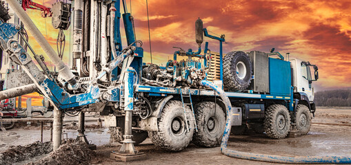 Fototapeta premium Drilling rig works on site at sunset. Close-up. Deep hole drilling. Geological exploration work. Mineral exploration. Powerful drill drills a well.