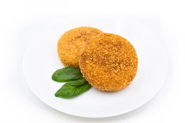 Fried breaded cutlets on the white plate on white background.