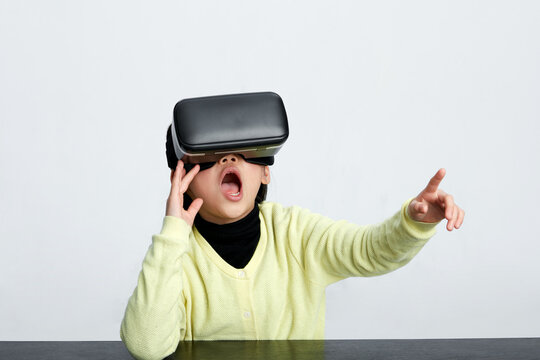 Asian little girl wearing vr glasses playing virtual indoors