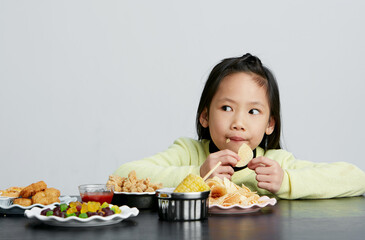 Asian little girl eating and playing indoors by herself