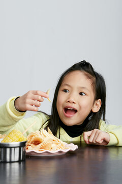 Asian little girl eating and playing indoors by herself