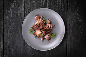 grilled seafood in a gray round plate on a dark wooden table
