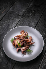 Seafood in a gray plate on a dark wooden table
