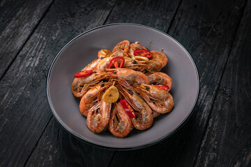 Seafood in a gray plate on a dark wooden table
