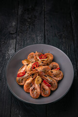 Seafood in a gray plate on a dark wooden table
