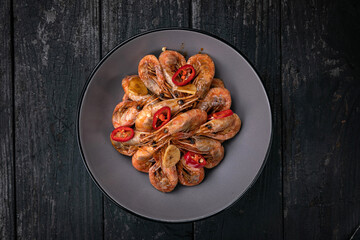 grilled seafood in a gray round plate on a dark wooden table
