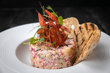 Olivier salad with seafood and caviar on a dark table
