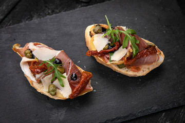 Bruschetta with meat on a dark wooden table

