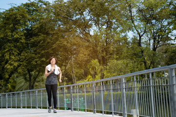 Beautiful Middle-aged Asian woman running in sportswear is smiling happy in park morning. Exercise make body healthy. Workout is health care Good