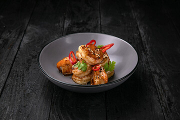 Seafood in a gray plate on a dark wooden table
