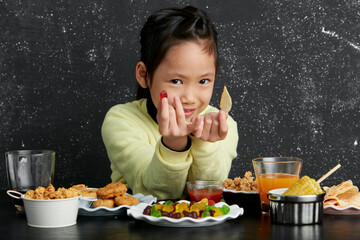 Asian little girl eating and playing indoors by herself