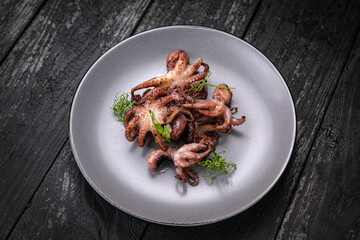 Seafood in a gray plate on a dark wooden table
