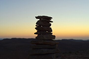 Cairn at sunrise, stones balances, pyramid of stones at sunset, concept of life balance, harmony and meditation. A pile of stones in desert mountains, crater Ramon, Israel. stack of rocks, stone tower