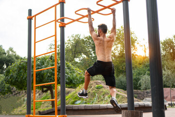 Muscular athletic man doing gymnastic exercises on the horizontal bar