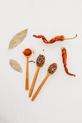 Spices in a wooden spoon. Herbs, curry, saffron, turmeric, cinnamon, bay leaf, peppers for cooking on a white background