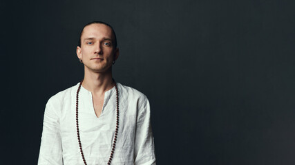 Fototapeta premium Yogi man in a white shirt on black background.