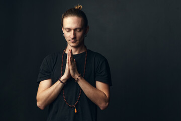 Portrait of a yogi man doing namaste on a black background.