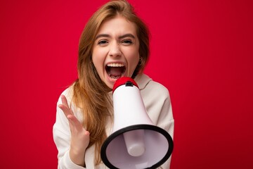Photo portrait of beautiful attractive positive happy joyful dark blonde young woman with sincere emotions wearing stylish white hoodie isolated over red background with copy space and yelling into