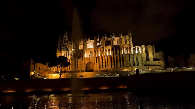 Night static shot of the Cathedral of Palma de Mallorca (La Seu) with fountain in the foreground - Spain