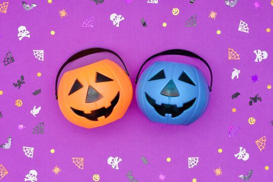Happy Halloween for everyone concept. Teal pumpkin and orange for sweets and non-food treats on purple backdrop with confetti frame. Blue pumpkin bucket as a symbol of allergy or a child with autism.
