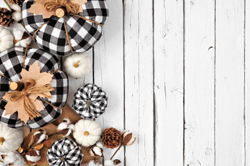 Modern farmhouse autumn side border over a white wood background. Black and white buffalo plaid pumpkins and rustic decor. Top view with copy space.