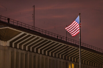 The US flag flutters in the wind in front of the US Embassy in Sri Lanka, on foreground of dark clouds at sunset.