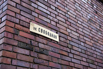A road sign on a red brick wall with the words Free . A red brick wall with a street sign.