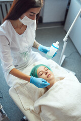 Beautician applies tonic to woman's face with a cotton pad. Skincare procedure in cosmetology clinic.