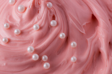 Pink icing frosting with small pearl sprinkles close up texture