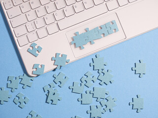 Puzzle elements on a laptop keyboard, software development, learning programming, creating large programs from small blocks, concept. Mosaic on a blue background