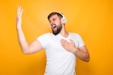 Fototapeta premium bearded man in white headphones sings loudly and gestures with his hands.