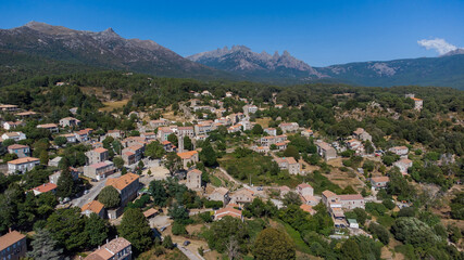 Fototapeta na wymiar Aerial view of the mountainous village of Quenza in the Alta Rocca region of the South of Corsica, France - Stone buildings in front of the famous Bavella Peaks
