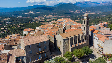 Fototapeta premium Aerial view of the Liberation Square and Church of Saint Mary of Sartène in the mountains of the South of Corsica, France - Regional capital, Sartène is mostly made of granite buildings