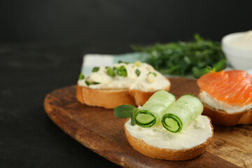 Delicious sandwiches with cream cheese and other ingredients on wooden board