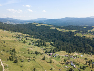 Fototapeta na wymiar Green mountains of the Ukrainian Carpathians on a sunny summer morning. Coniferous trees on the mountain slopes and green grass. Aerial drone view.