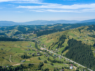 Green mountains of the Ukrainian Carpathians on a sunny summer morning. Coniferous trees on the mountain slopes and green grass. Aerial drone view.