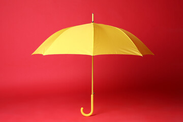 Stylish open yellow umbrella on red background