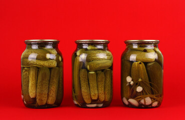 Three jars of pickles on a red background