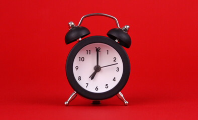 Black alarm clock on red background