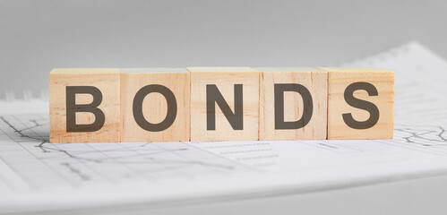bonds is written on light wooden blocks. the word is located on a sheet with charts and graphs