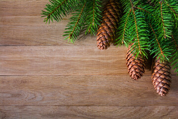 Christmas background with fir branches with cones on a wooden background. Copy space