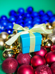 colored Christmas toys are scattered on the table and a gift box with a bow